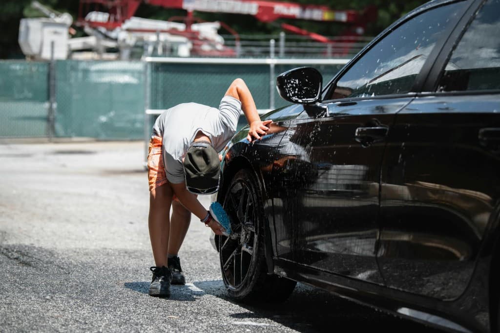 Professional detailer cleaning a vehicle wheel with care